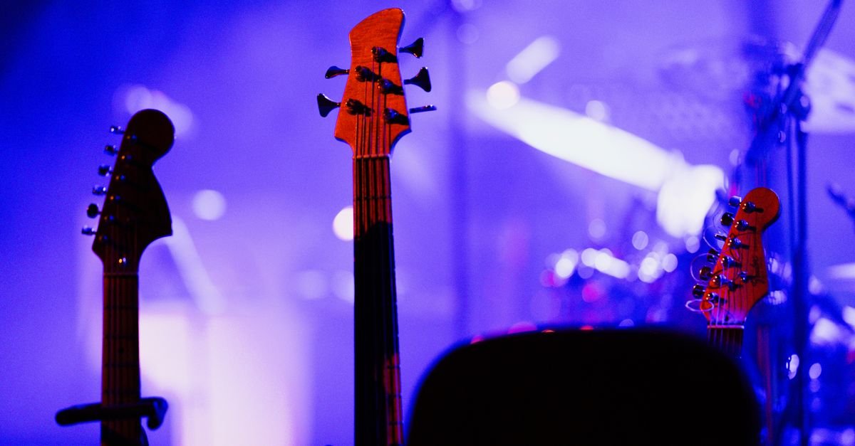 Guitarras em suportes no palco sob iluminação azul de show