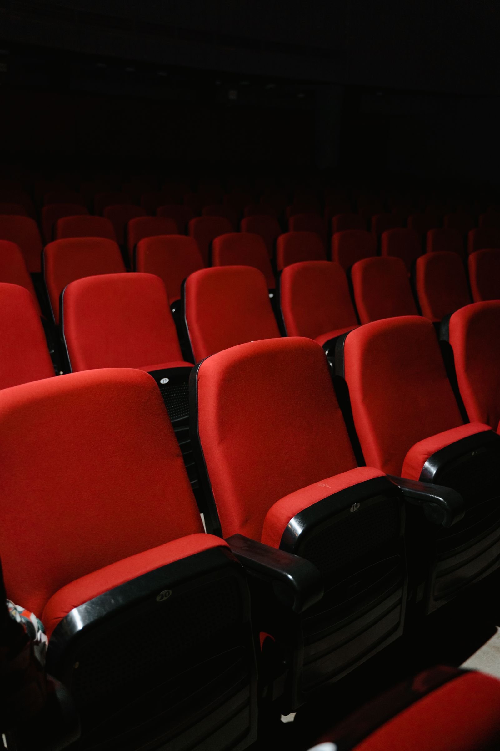 Fileiras de poltronas vermelhas vazias em plateia de teatro