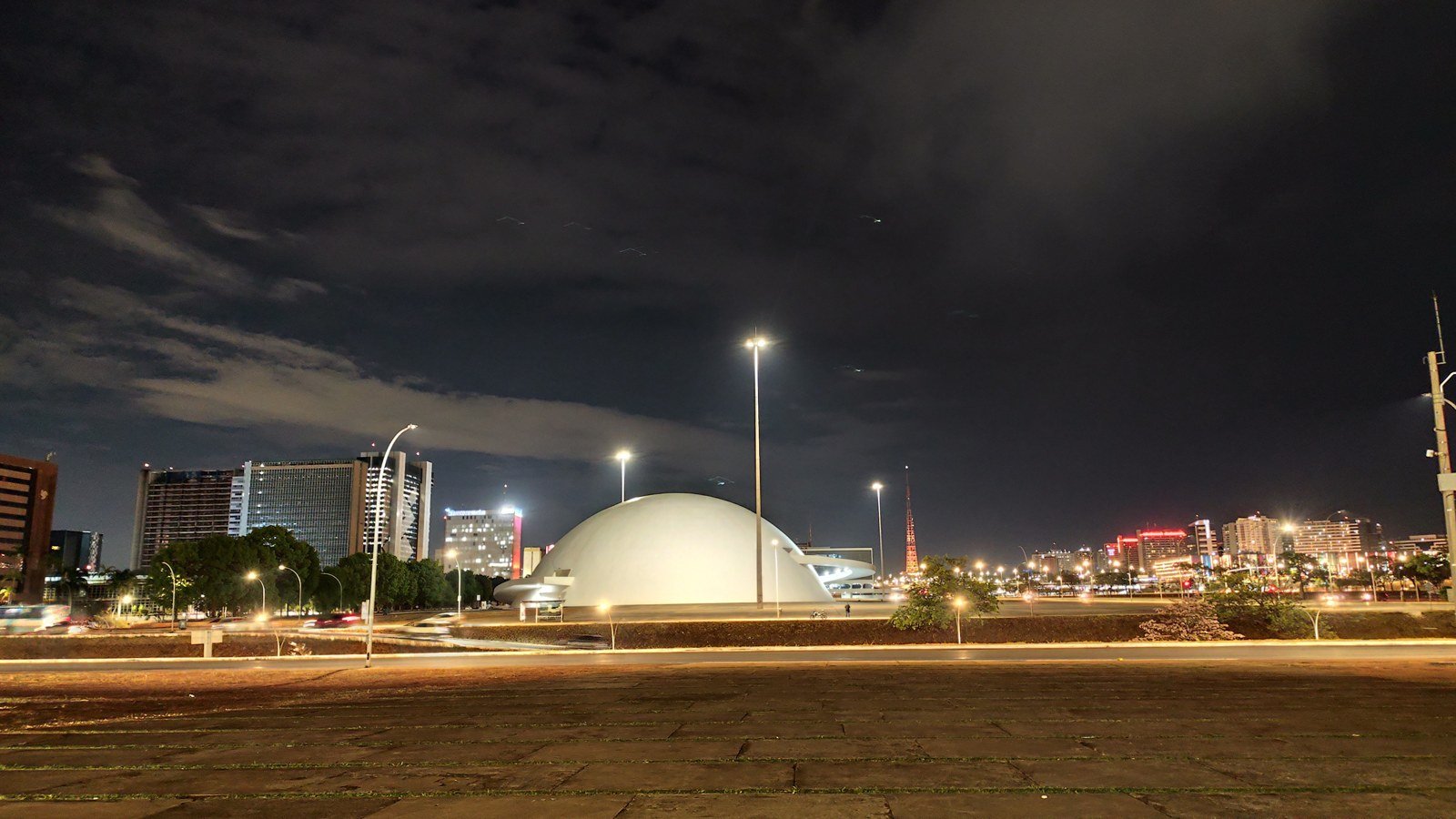 Cúpula branca do Museu Nacional da República à noite, com a cidade iluminada ao fundo