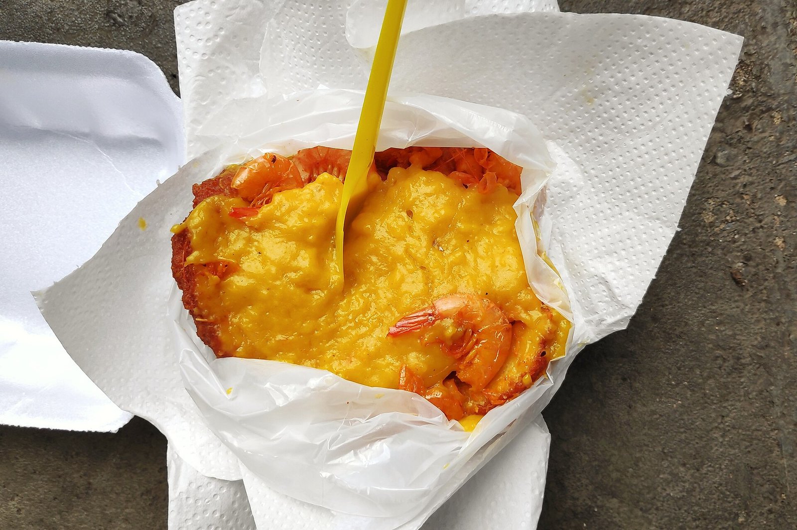 Acarajé aberto com vatapá e camarões, servido em papel branco
