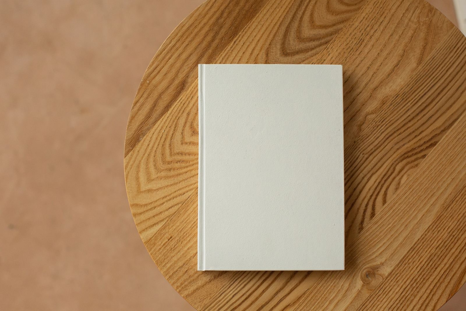 Livro de capa branca sobre mesa redonda de madeira