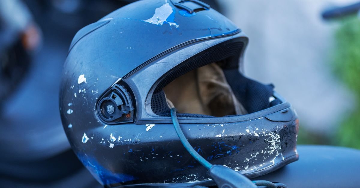 Capacete de motociclista azul e desgastado apoiado sobre uma moto, em plano fechado
