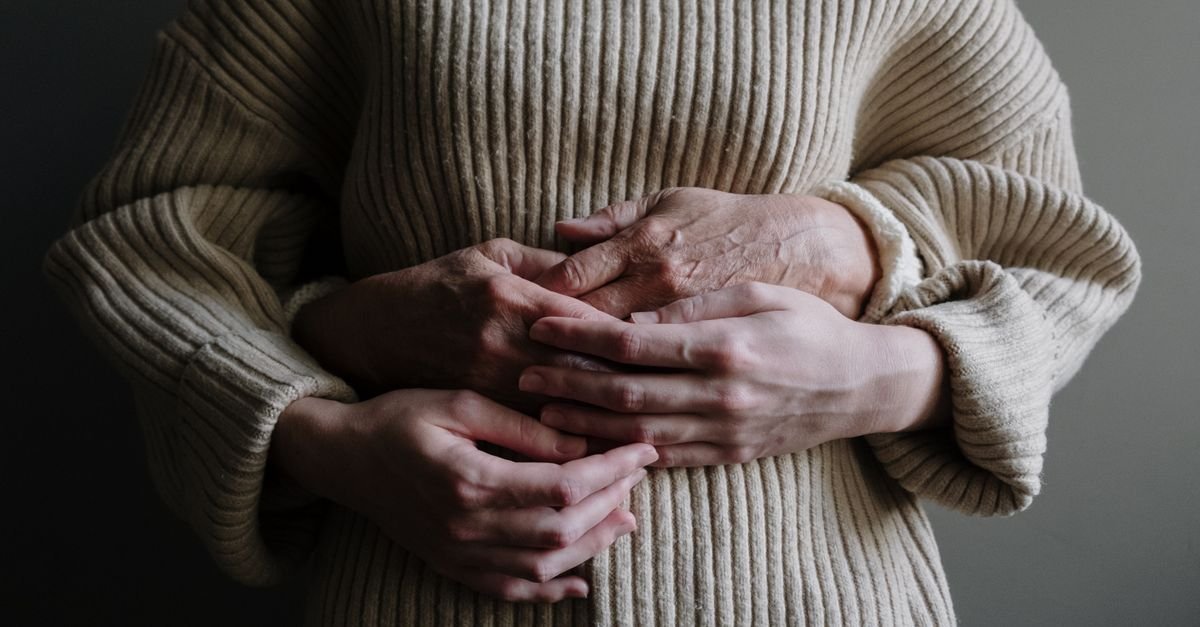Close de duas pessoas abraçadas, com as mãos entrelaçadas sobre suéter de tricô