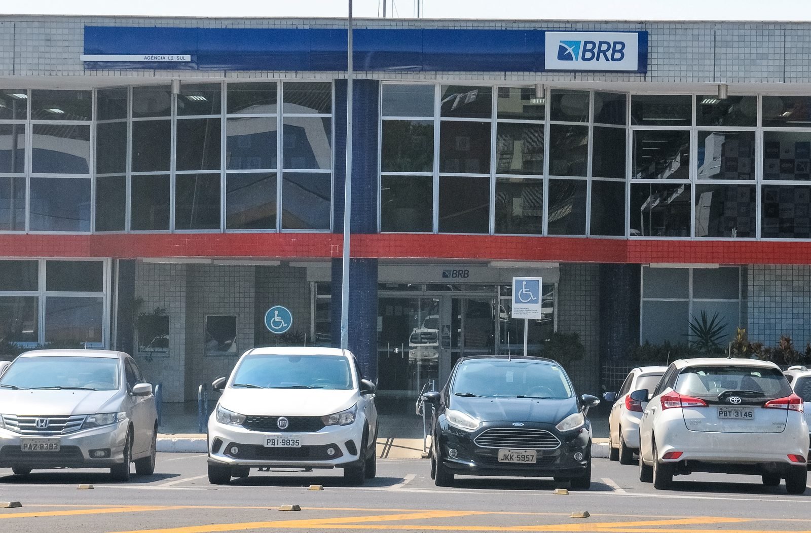 Fachada da agência do BRB na L2 Sul, em Brasília, com carros estacionados em frente