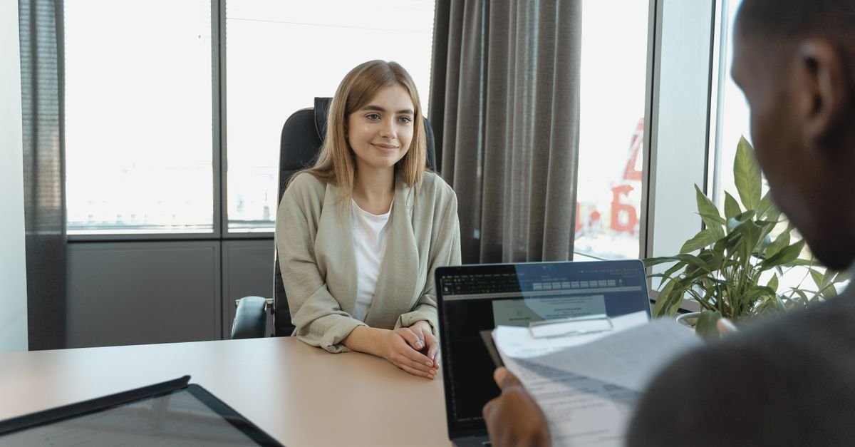 Candidata sentada diante de recrutador que segura um currículo impresso durante entrevista de emprego