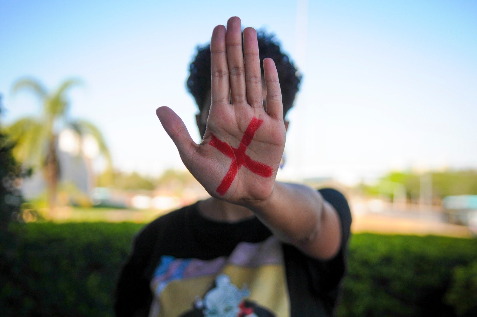 Mão com um X vermelho pintado na palma, símbolo do Sinal Vermelho contra a violência doméstica