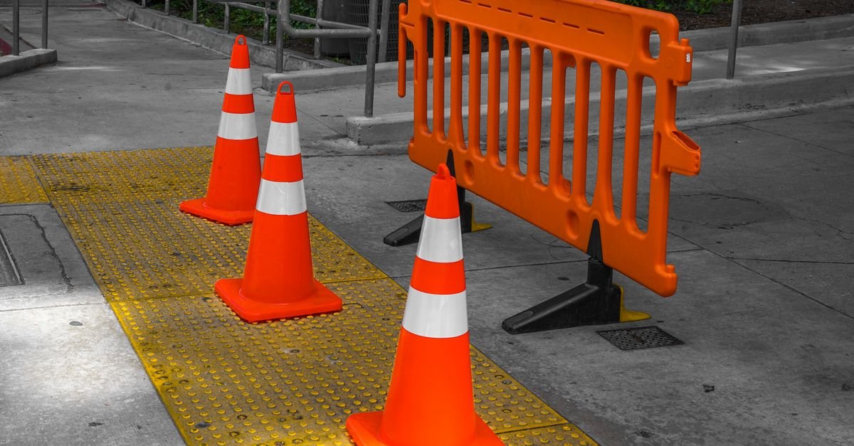 Cones laranja e barreira plástica isolando trecho de calçada e via