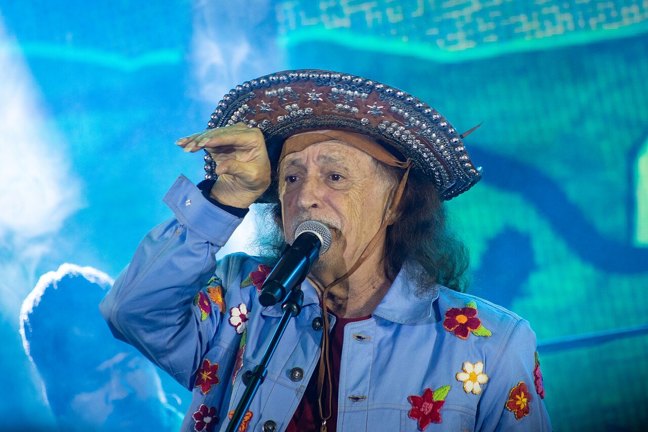 Alceu Valença canta ao microfone usando chapéu de couro decorado durante show de São João