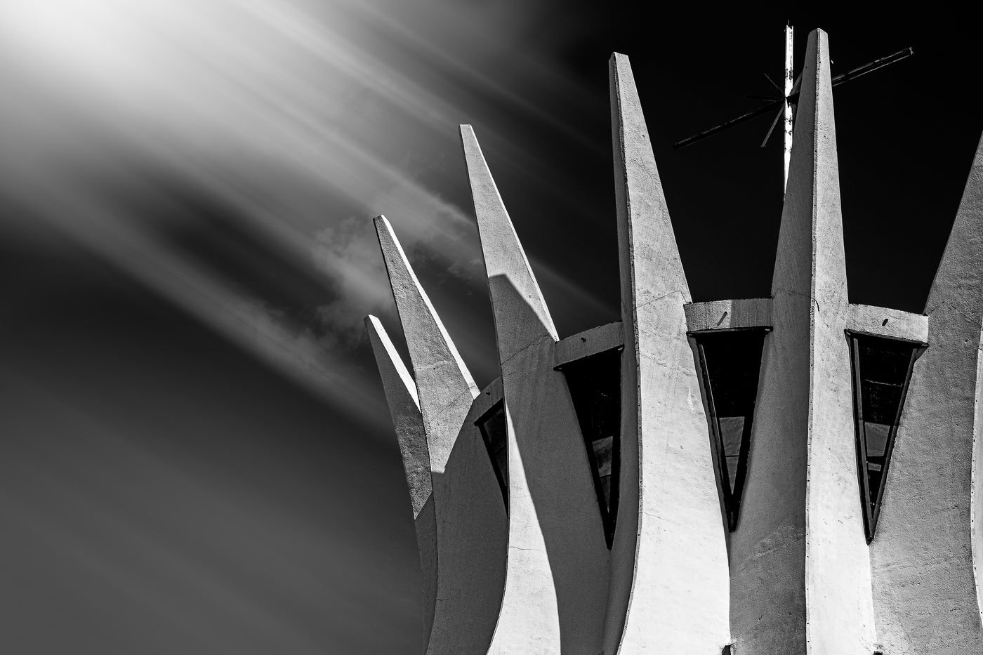 Torres de concreto da Catedral de Brasília em preto e branco, com raios de luz ao fundo