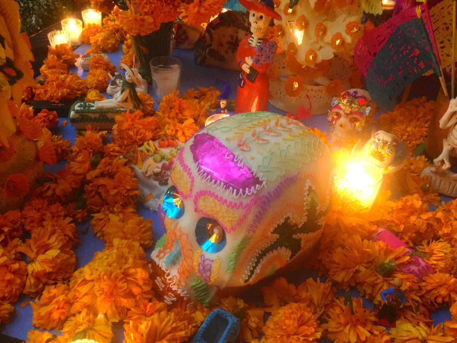 Caveira de açúcar colorida cercada de flores de cempasúchil e velas em altar do Dia de Muertos