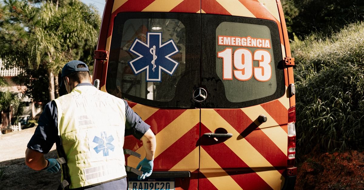 Socorrista de colete refletivo de costas junto à traseira de uma ambulância brasileira com o número de emergência 193