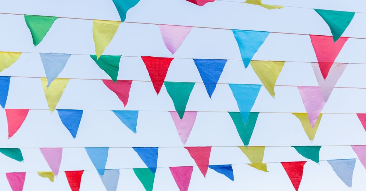 Fileiras de bandeirinhas coloridas de festa junina estendidas contra o céu claro