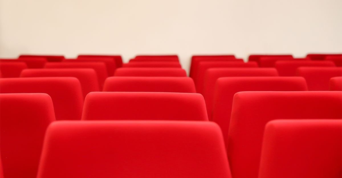 Fileiras de poltronas vermelhas vazias em plateia de teatro
