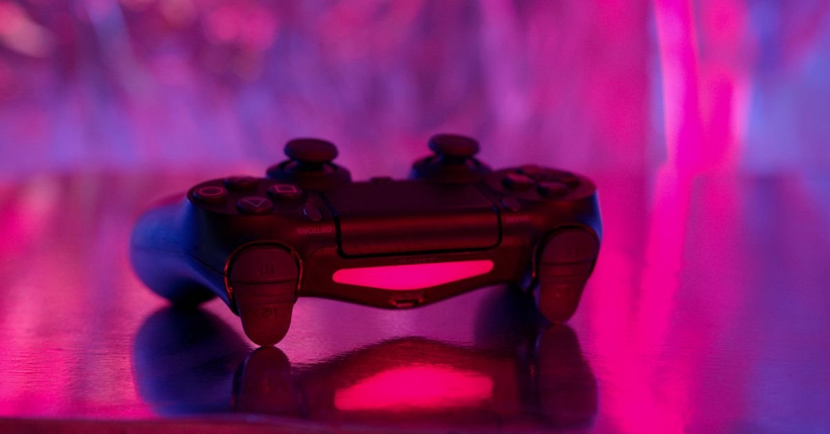 Controle de videogame sem fio sobre superfície, iluminado por luz neon rosa e azul
