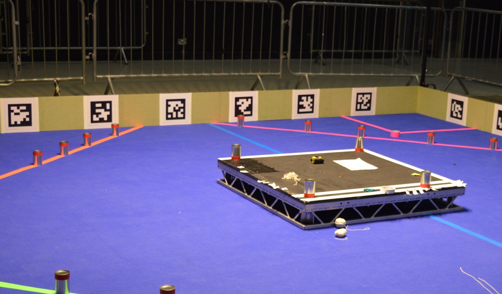 Arena de competição de robótica com piso azul e marcadores nas paredes