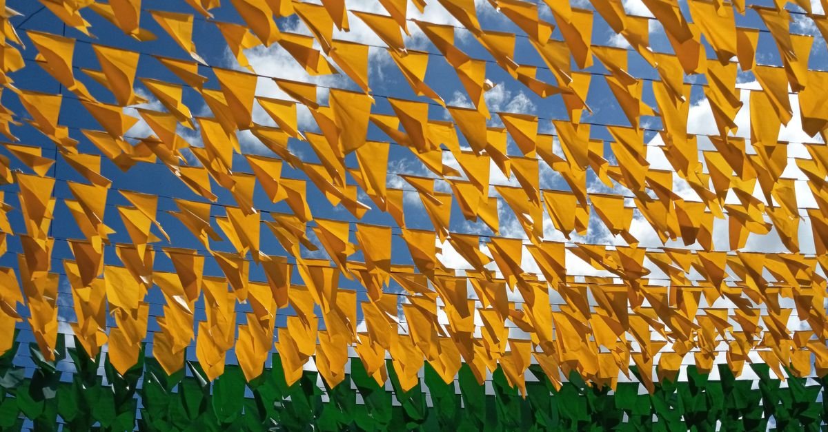 Bandeirinhas amarelas e verdes de festa junina estendidas contra o céu azul