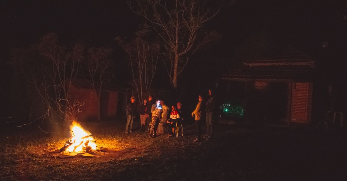 Fogueira acesa a noite com grupo de pessoas reunido ao redor