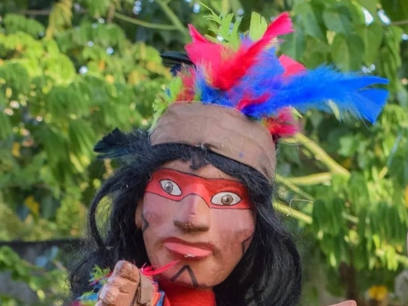Boneco de mamulengo com cocar de penas coloridas, imagem ilustrativa de teatro de animacao