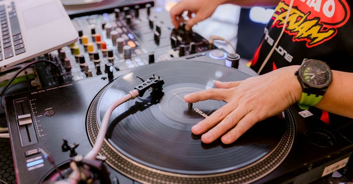 Mãos de DJ sobre toca-discos de vinil em evento de música