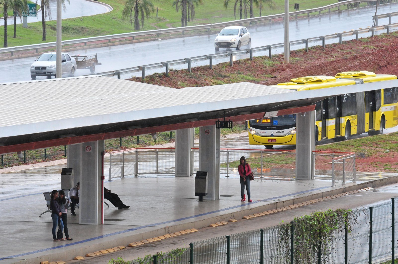 Estação do BRT Sul com articulado amarelo chegando e passageiros esperando na plataforma