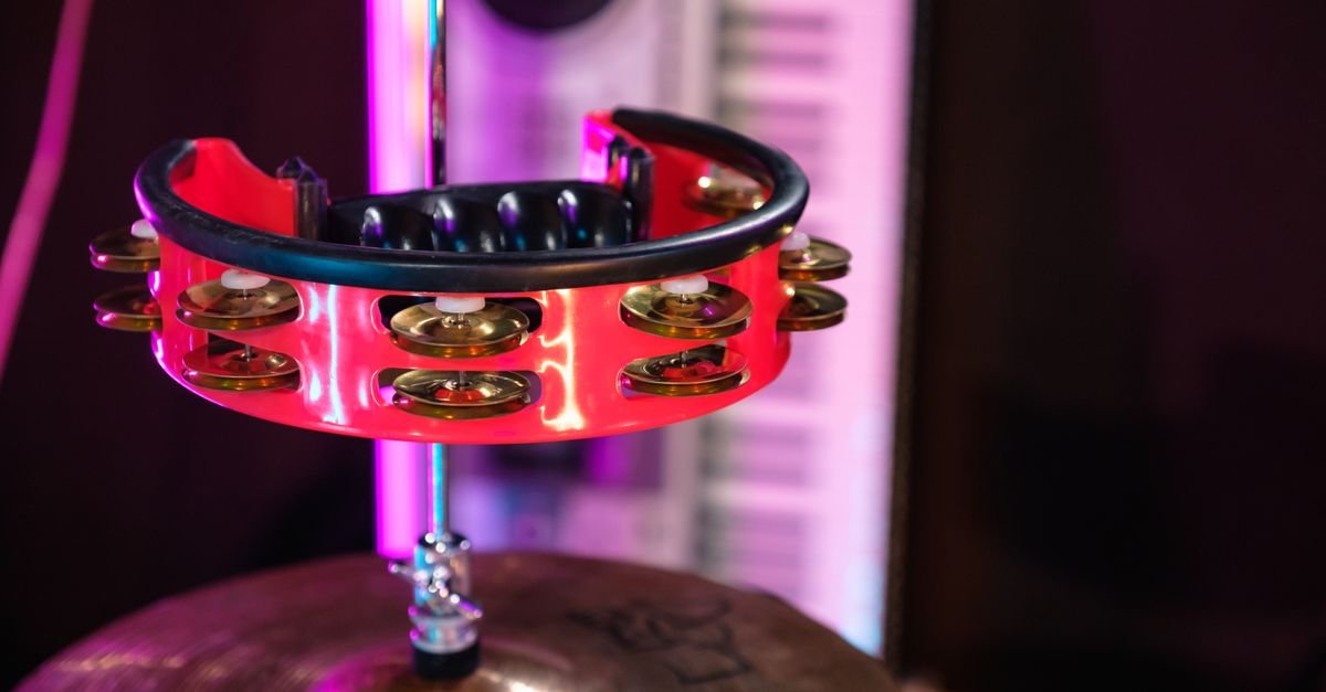 Pandeiro apoiado sobre prato de bateria em palco iluminado