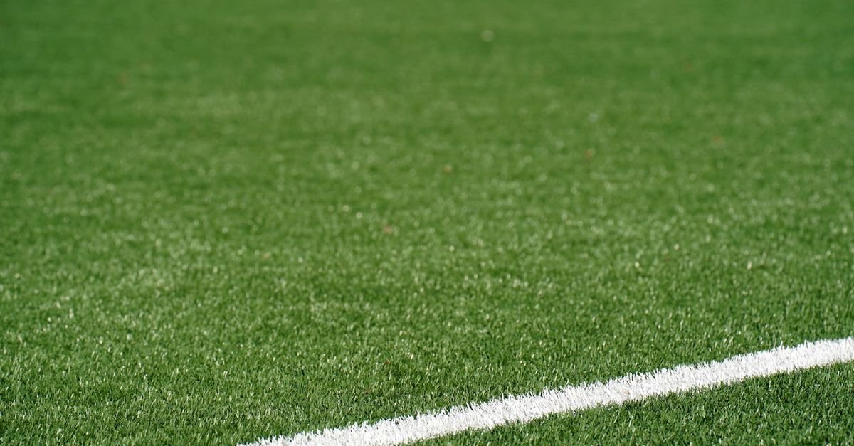 Gramado sintético de campo de futebol com linha de marcação branca