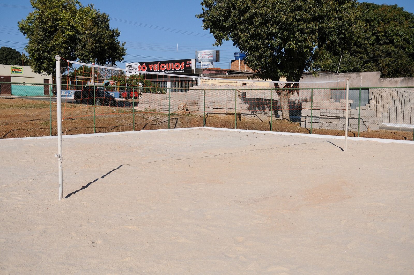 Quadra de areia em área comunitária do Arapoanga, com comércio local ao fundo