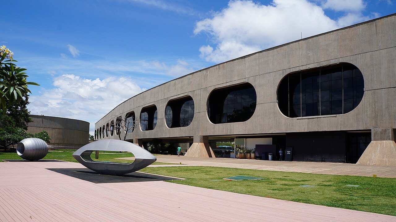 Fachada curva do Centro Cultural Banco do Brasil de Brasilia vista do jardim externo em dia de ceu azul