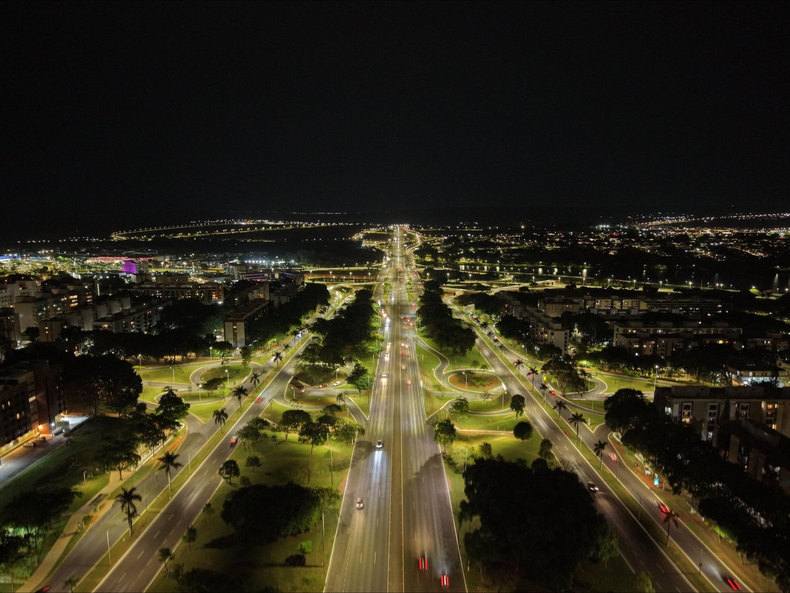 Vista aérea noturna de avenida do Plano Piloto de Brasília com iluminação pública acesa
