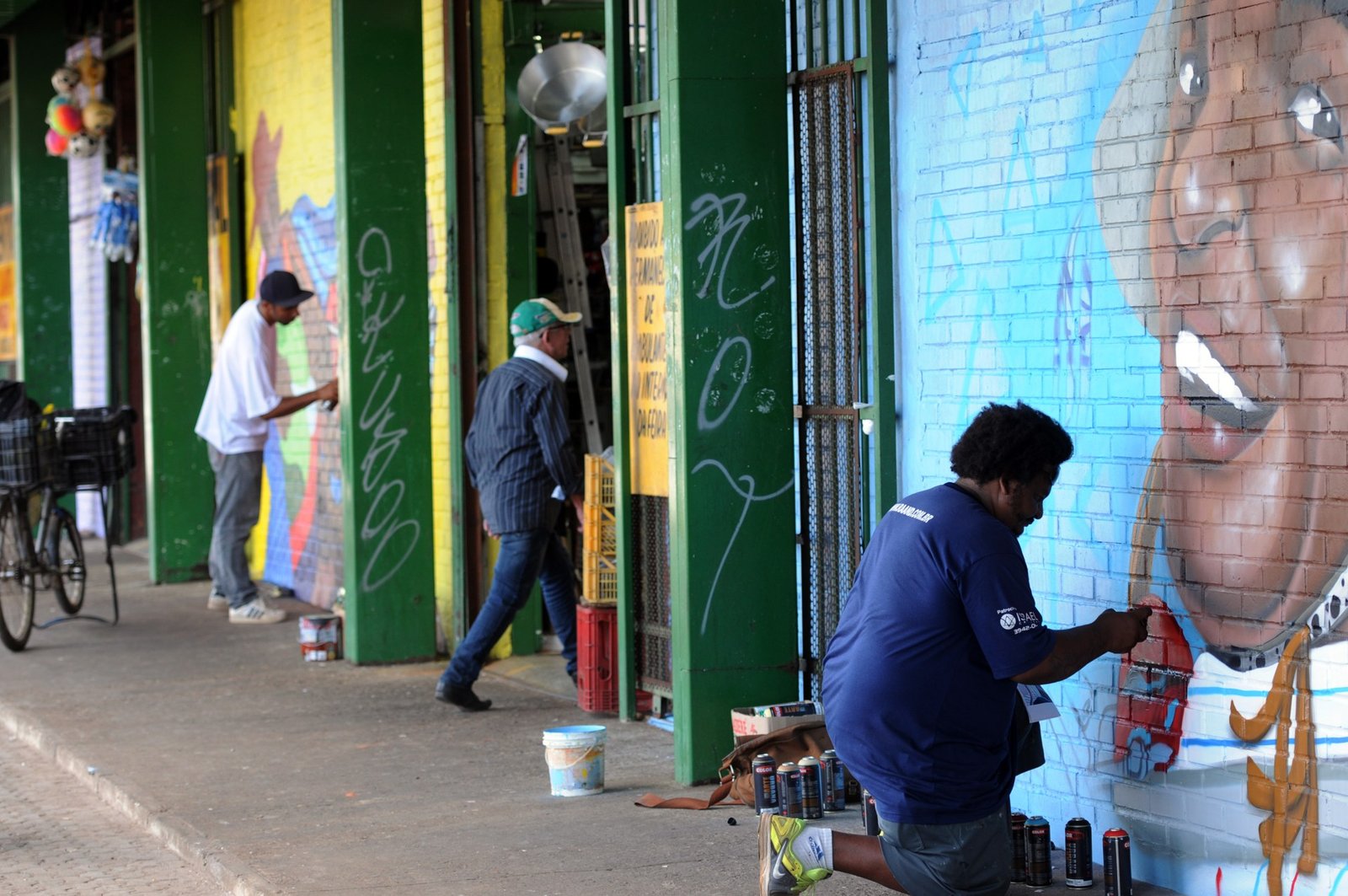 Artistas pintam grafite em muro sob a marquise da área central de Ceilândia
