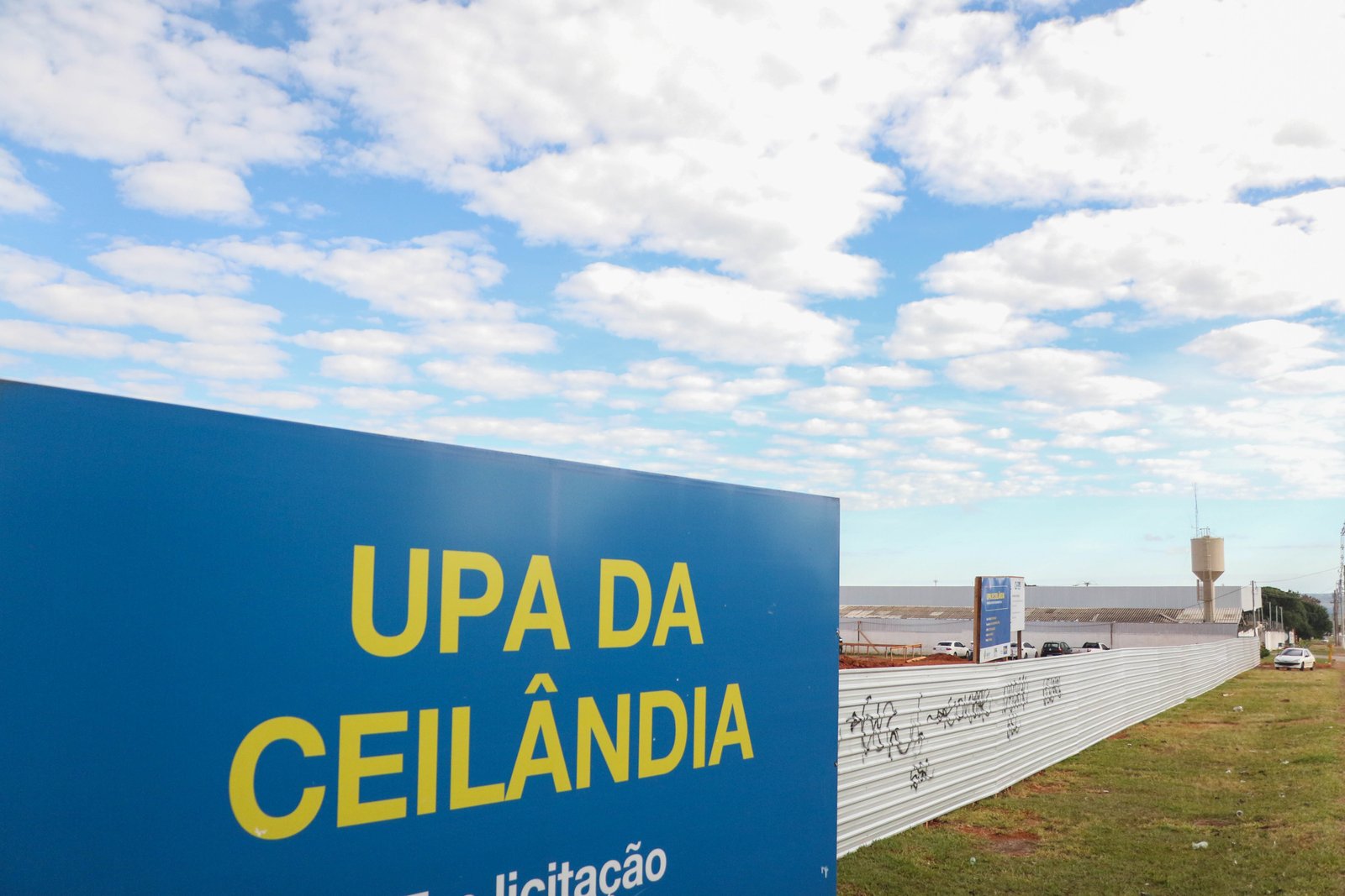 Placa azul com o nome UPA da Ceilândia em terreno cercado por tapume, durante a obra da unidade, em foto de arquivo