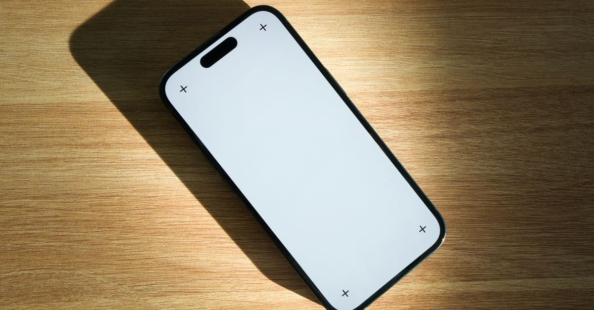 Celular com a tela em branco apoiado sobre uma mesa de madeira