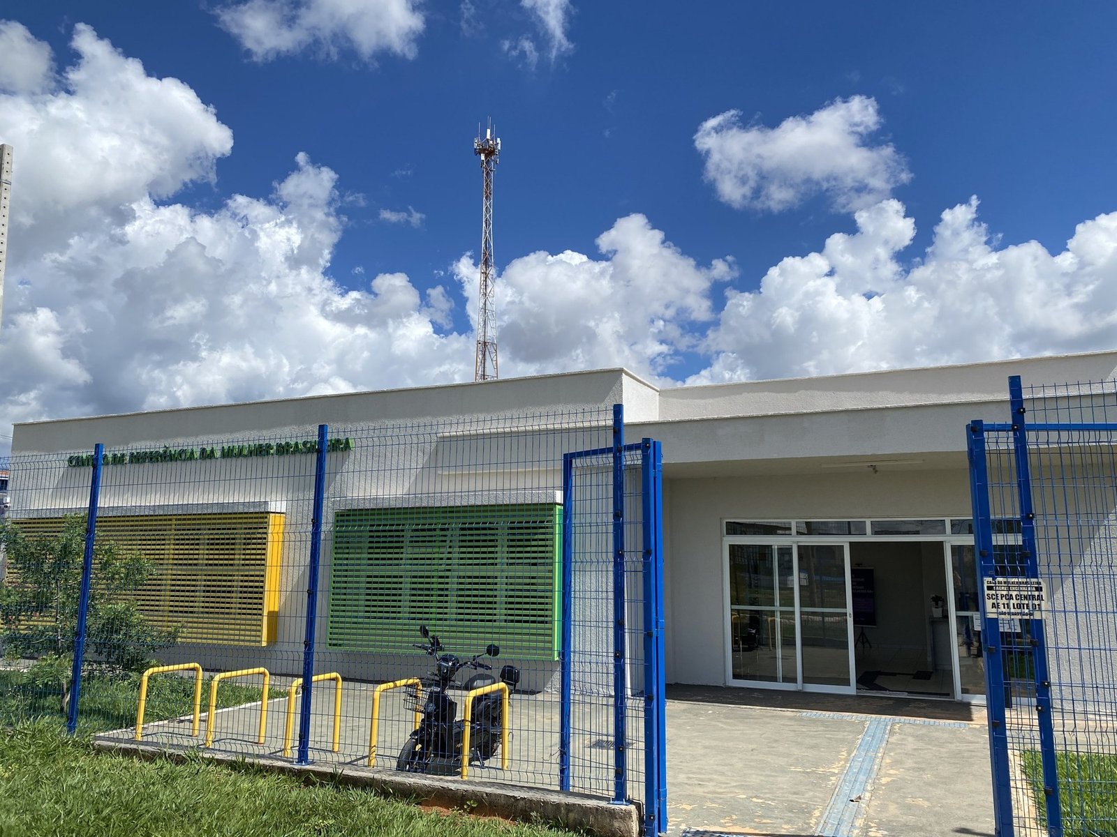 Fachada de uma unidade do Centro de Referência da Mulher Brasileira, com cercas azuis e venezianas verdes e amarelas