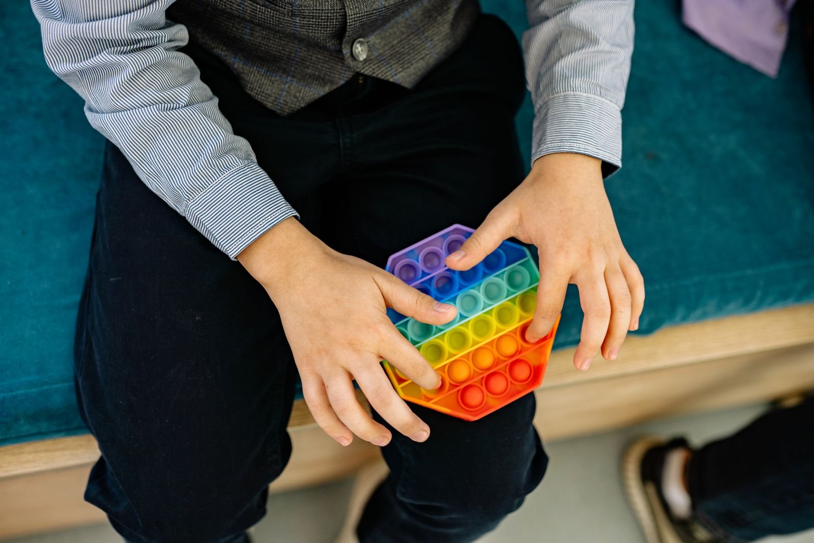 Mãos de criança manuseando um brinquedo sensorial colorido