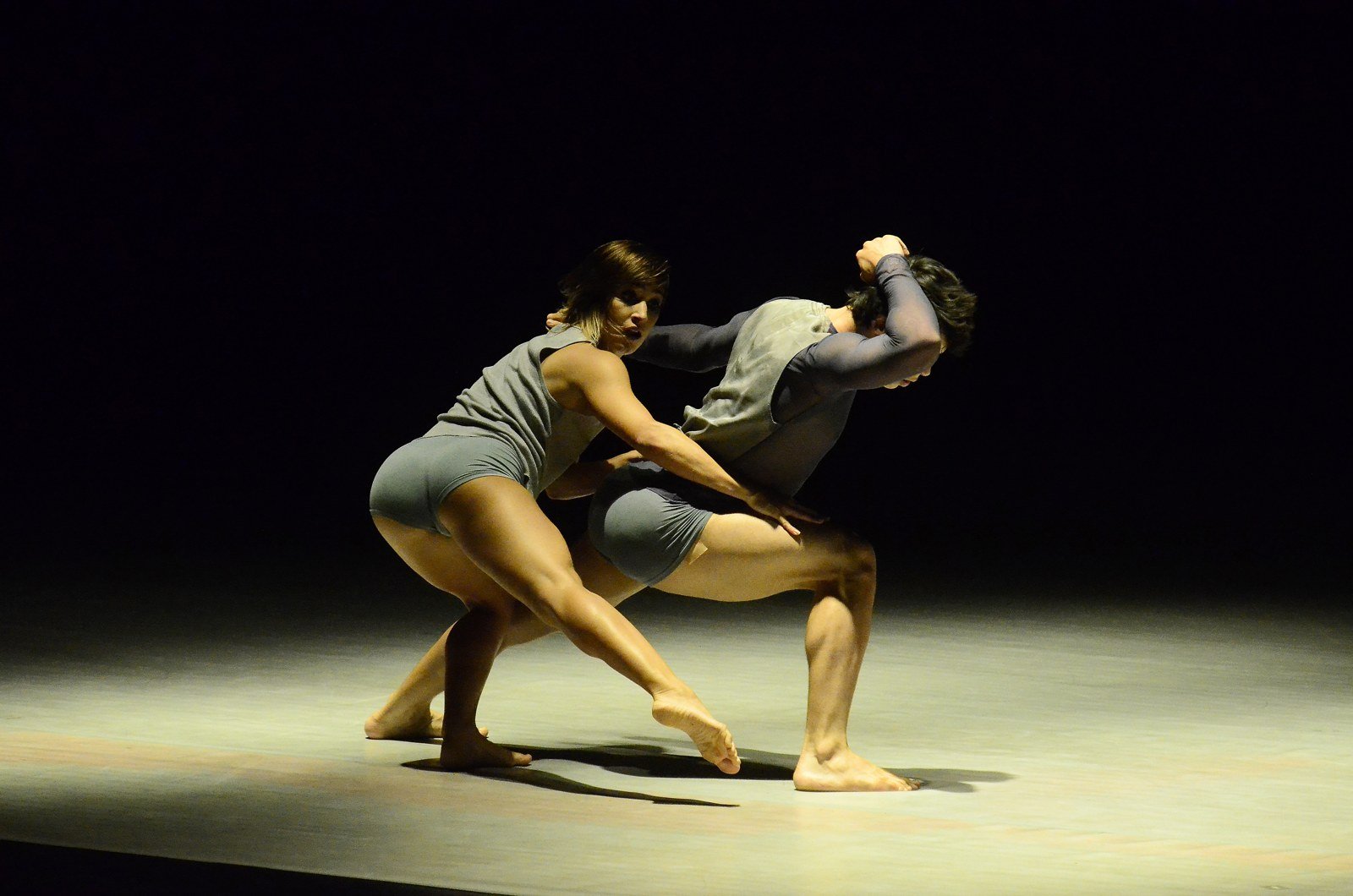 Dois bailarinos da Quasar Cia de Dança em movimento de contato no palco