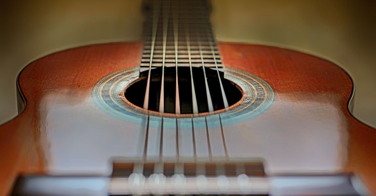 Close de violão clássico com foco nas cordas e na boca do instrumento