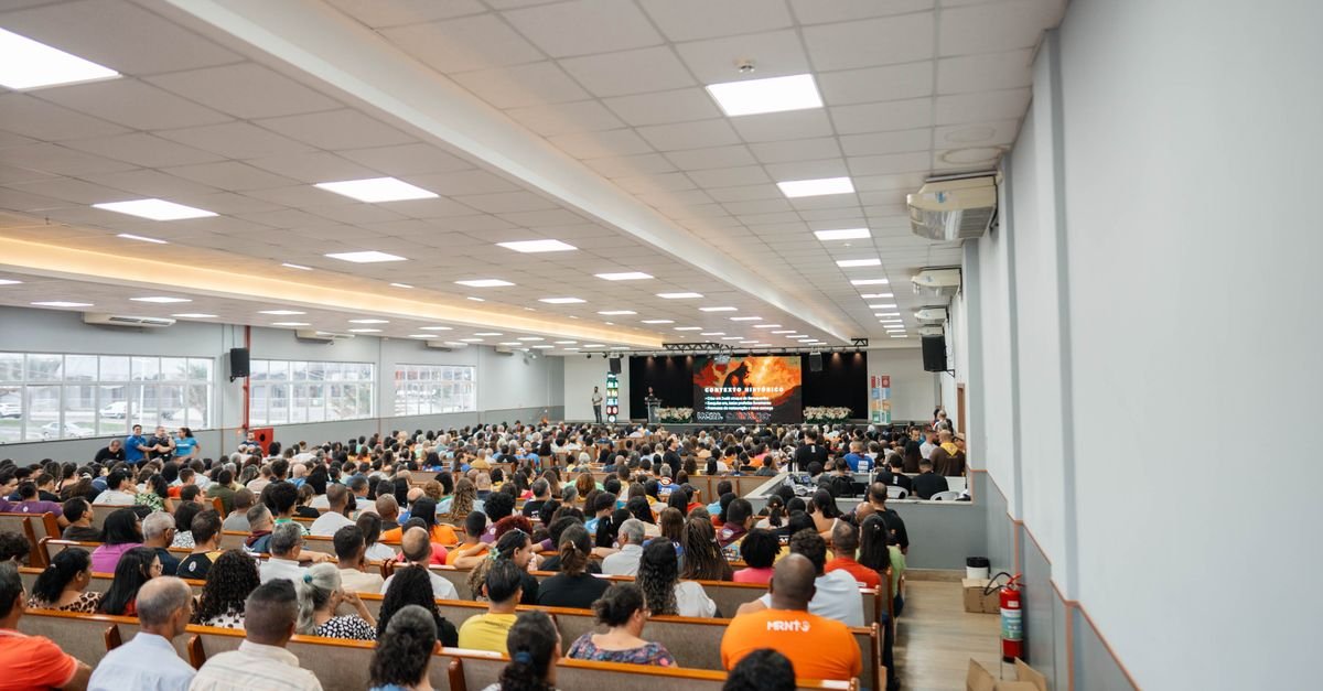 Plateia lotada acompanha palestra em auditório com telão ao fundo