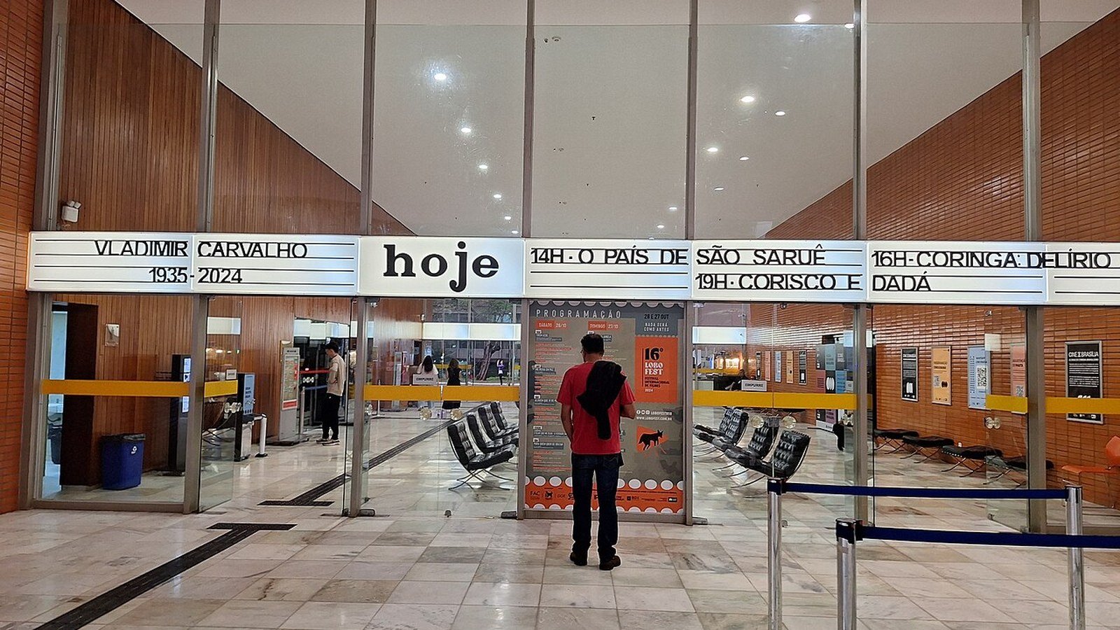 Saguão do Cine Brasília com o painel de programação do dia acima das portas de vidro