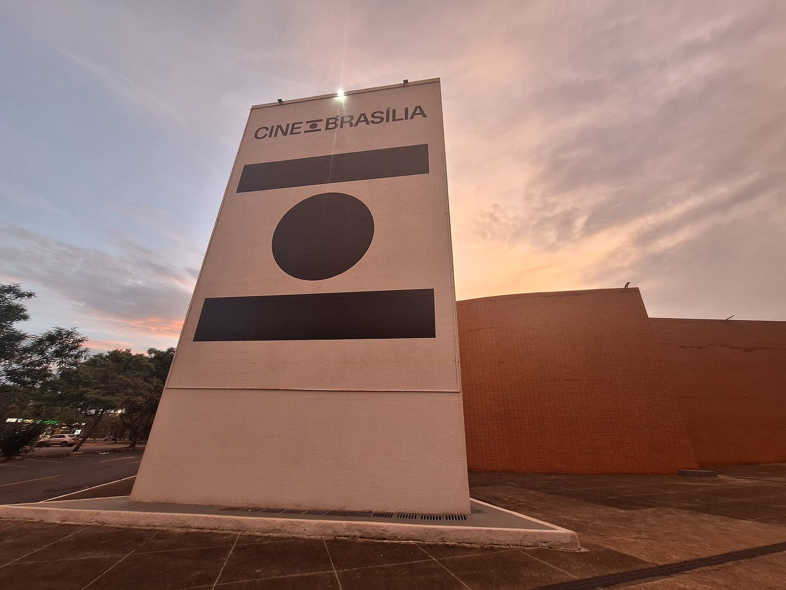 Totem com o letreiro Cine Brasília em frente ao prédio do cinema, ao entardecer