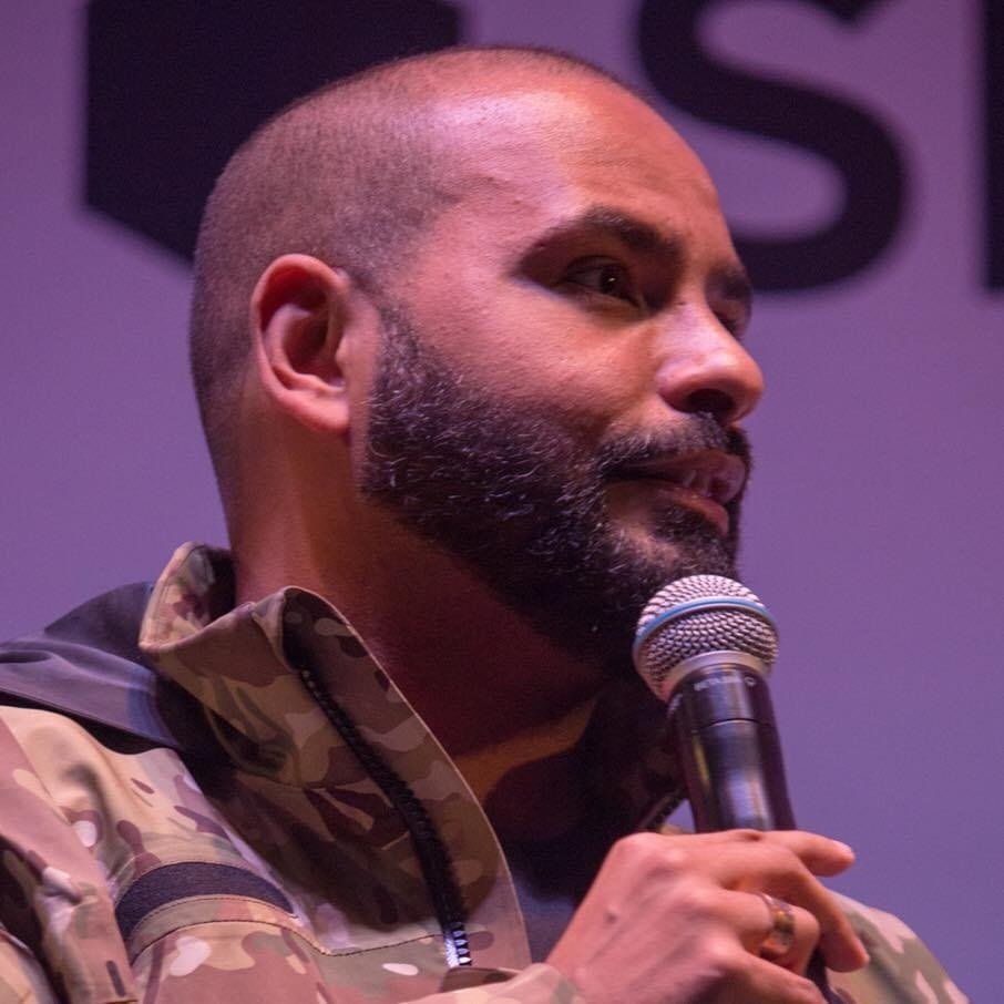 Michel Alcoforado segurando um microfone durante uma fala em palco