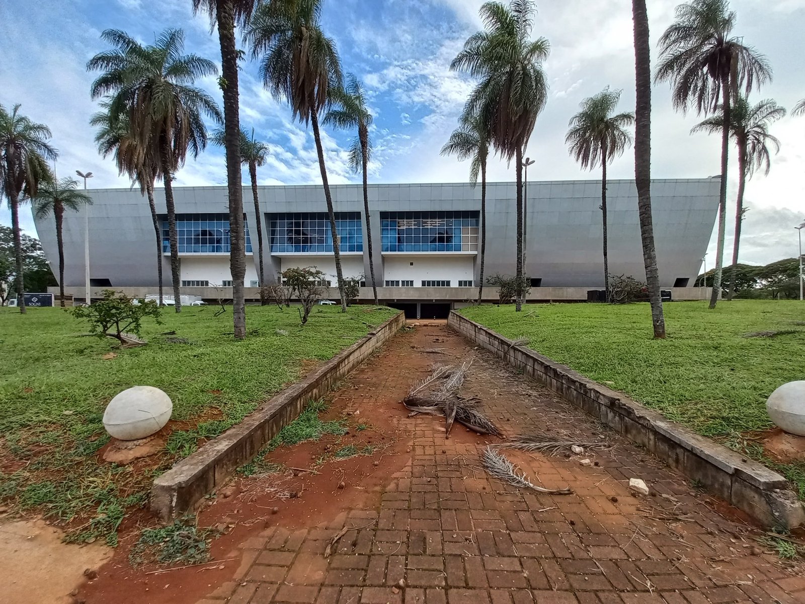 Fachada do Centro de Convenções Ulysses Guimarães, em Brasília, com palmeiras e caminho de pedras à frente