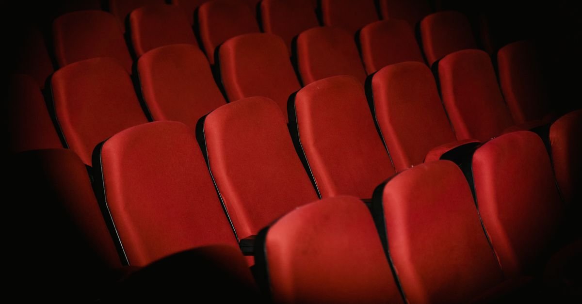Fileiras de poltronas vermelhas vazias em sala de teatro