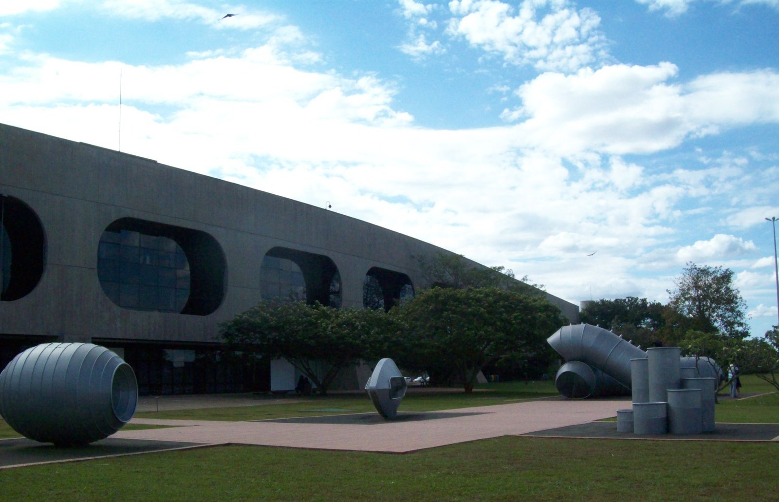 Fachada curva de concreto do CCBB Brasília com esculturas metálicas no gramado, em foto de arquivo
