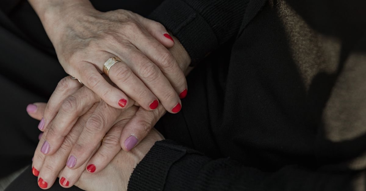 Mãos de uma pessoa idosa apoiadas sobre as mãos de outra pessoa, em gesto de acolhimento
