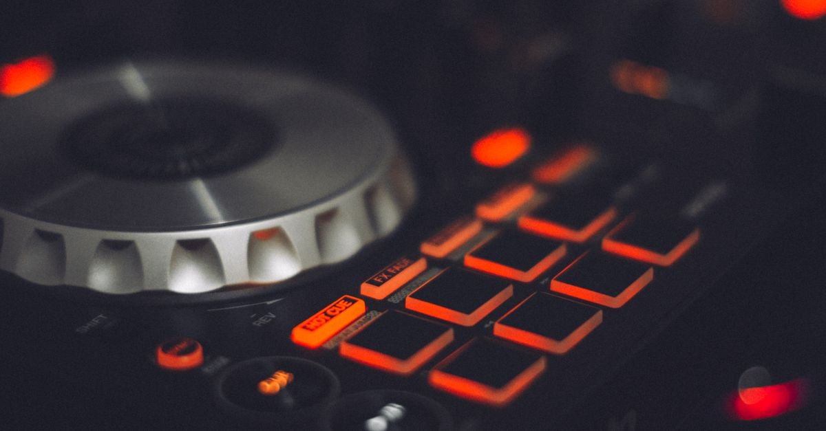 Close de uma controladora de DJ com botões iluminados em vermelho e jog wheel metálico