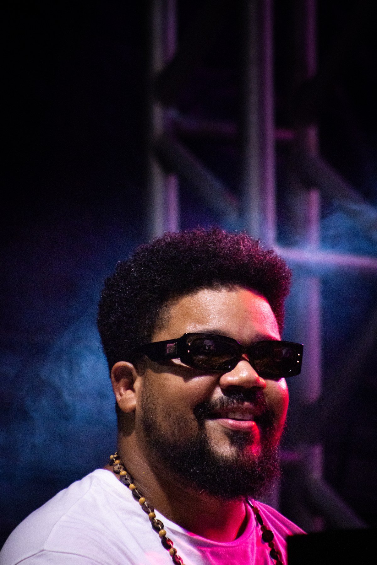 Retrato do pianista Amaro Freitas sorrindo, de óculos escuros, em apresentação em 2025