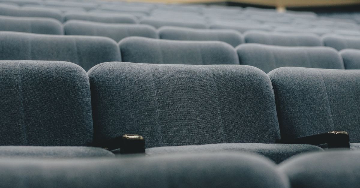 Fileiras de poltronas azuis vazias em auditório