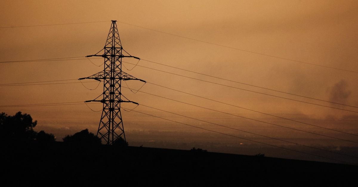 Silhueta de torre de transmissão de energia elétrica com cabos ao entardecer