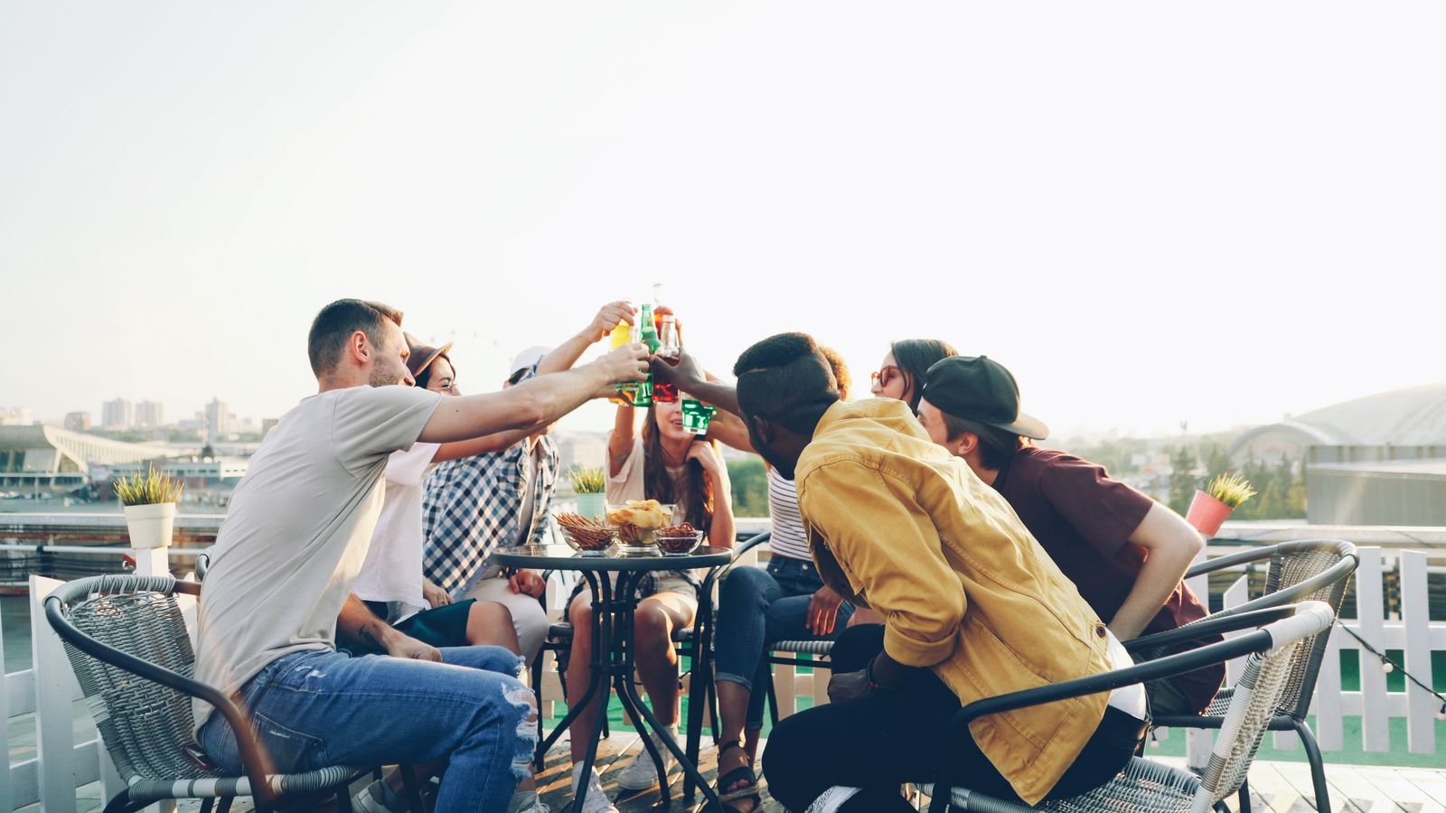Grupo de amigos brindando em mesa num terraço ao fim da tarde, foto de banco de imagens sem relação com a festa