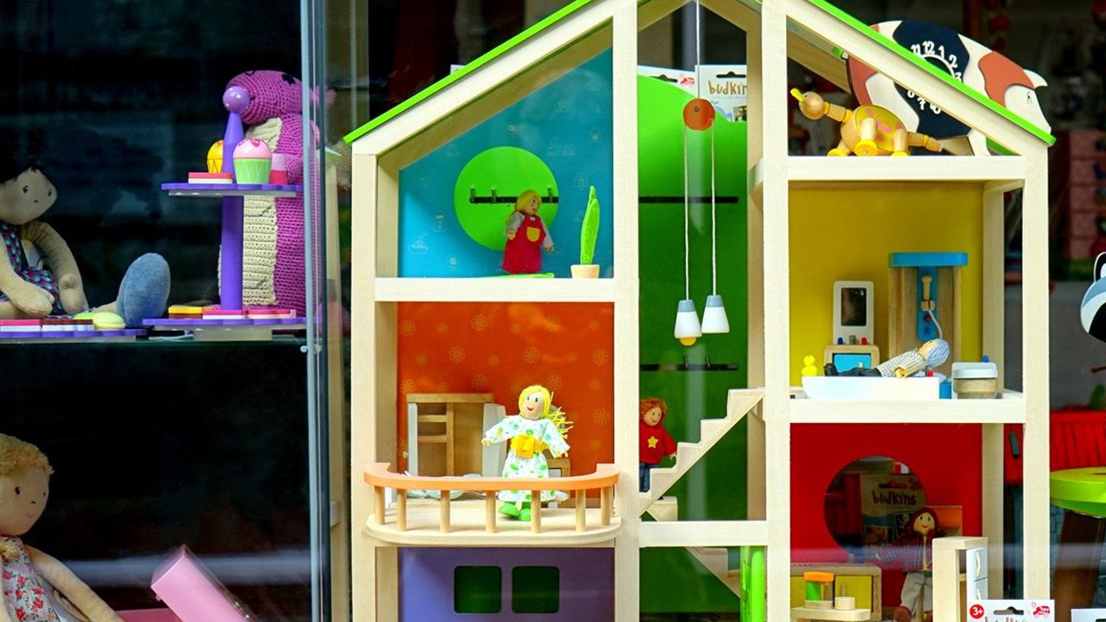 Vitrine de loja de brinquedos com casa de bonecas de madeira colorida e bonecas de pano